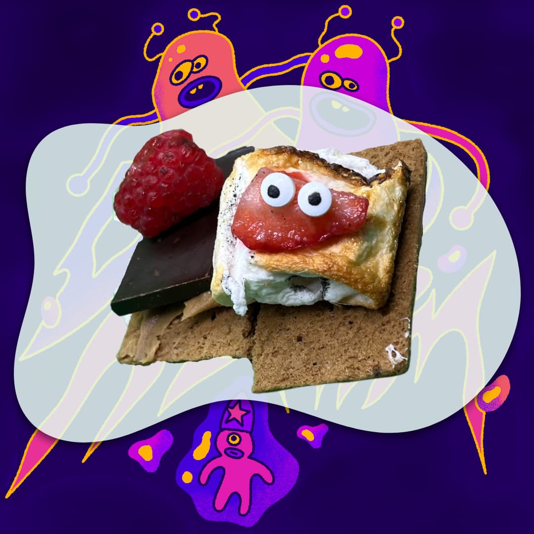 A s'more with candy eyes photographed against a purple cartoon-monster backdrop